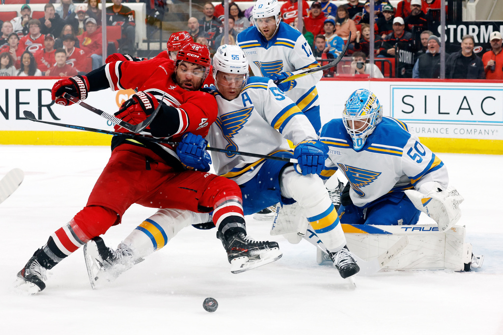 Carolina Hurricanes' Jordan Martinook (48) battles with St. Louis Blues' Colton Parayko (55) for the puck with goaltender Jordan Binnington (50) looking on during the second period of an NHL hockey game in Raleigh, N.C., Thursday, March 12, 2026. (AP Photo/Karl DeBlaker)