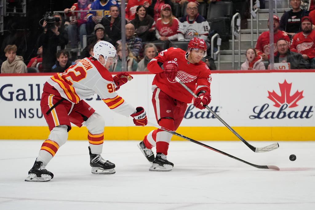 Detroit Red Wings right wing Patrick Kane (88) shoots on Calgary Flames defenseman Matvei Gridin (94) in the first period of an NHL hockey game Monday, March 16, 2026, in Detroit. (AP Photo/Paul Sancya)