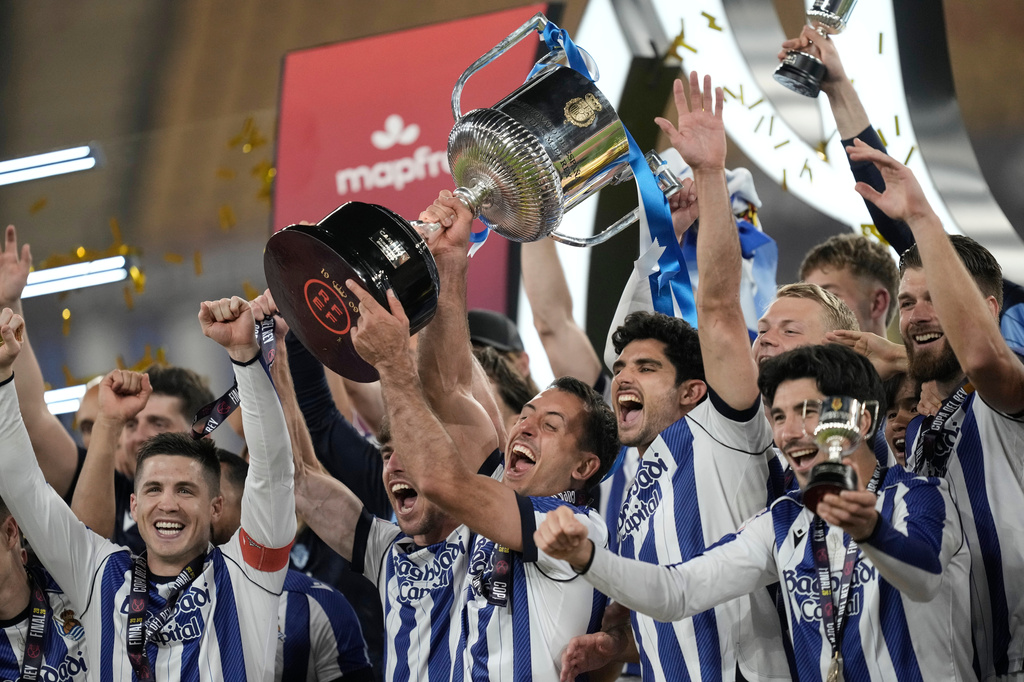 Real Sociedad's Mikel Oyarzabal, centre, lifts the trophy after the Copa del Rey final soccer match between Atletico Madrid and Real Sociedad in Seville, Spain, Saturday, April. 18, 2026. (AP Photo/Jose Breton)