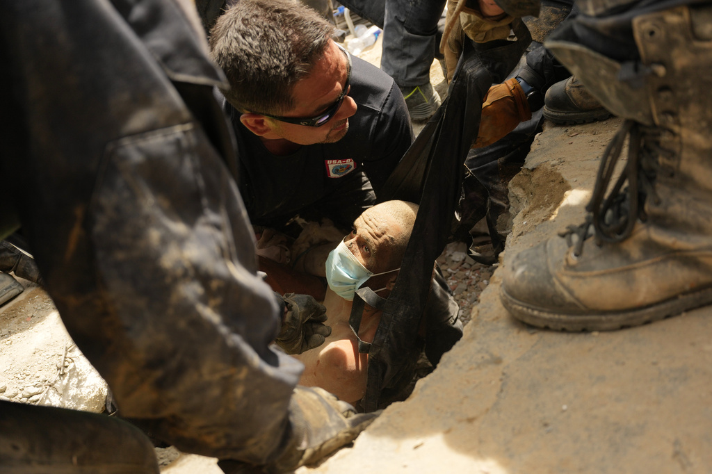 FILE - U.S. firefighters from Fairfax County pull a survivor from the rubble of a building that collapsed in twin earthquakes in La Guaira, Venezuela, June 28, 2026. (AP Photo/Matias Delacroix, File)