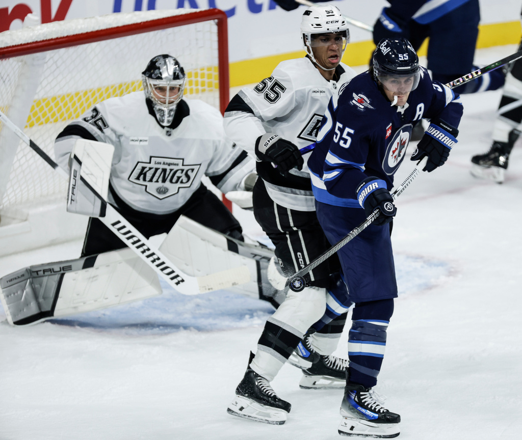 Winnipeg Jets' Mark Scheifele (55) attempts to tip the puck as Los Angeles Kings' Quinton Byfield (55) defends during the first period of an NHL game in Winnipeg, Manitoba, Saturday, Oct. 11, 2025. (John Woods/The Canadian Press via AP)