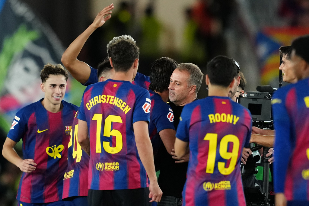 Barcelona players embrace Barcelona head coach Hansi Flick, center, celebrating after defeating Real Madrid 2-0 to win the Spanish La Liga soccer championship with three rounds to spare, in Barcelona, Spain, Sunday, May 10, 2026. (AP Photo/Joan Mateu Parra)