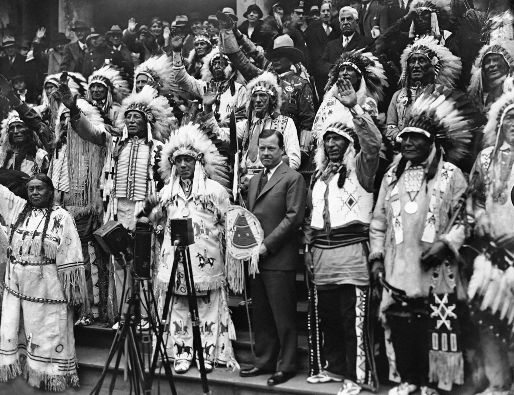FILE - Mayor Joseph V. McKee, center, stands with Sioux chieftains, in full tribal regalia, who met with him at New York City Hall, Nov. 18, 1932, in New York. (AP File Photo)