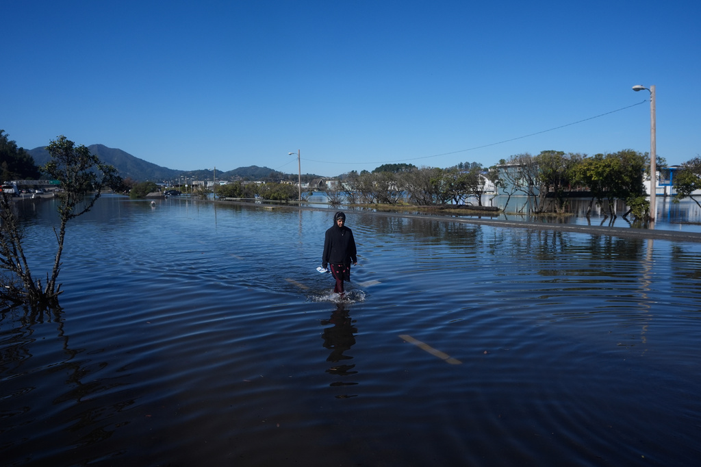 A woman wades through a flooded road in Sausalito, Calif., Wednesday, Oct. 28, 2026. (AP Photo/Jeff Chiu)