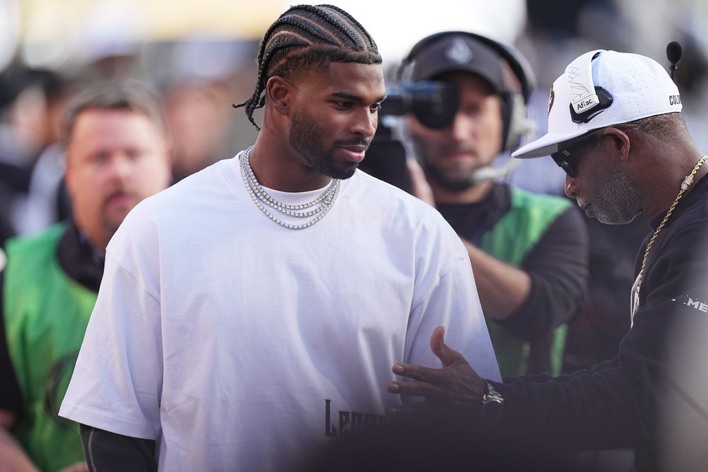 Cleveland Browns quarterback Shedeur Sanders, left, confers with his father, Colorado head coach Deion Sanders, before the first half of an NCAA college football game against Arizona Saturday, Nov. 1, 2025, in Boulder, Colo. (AP Photo/David Zalubowski)