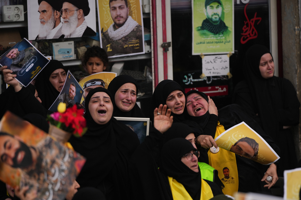Mourners grieve during a mass funeral procession of Hezbollah fighters who were killed before the ceasefire in the war between Hezbollah and Israel, in the southern village of Kfar Sir, Lebanon, Tuesday, April 21, 2026. (AP Photo/Hassan Ammar)