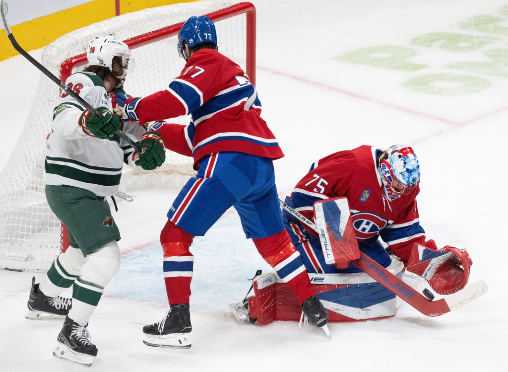 Montreal Canadiens goaltender Jakub Dobes (75) makes a save as Minnesota Wild's Ryan Hartman (38) and Canadiens' Kirby Dach (77) battle for the rebound during the second period of an NHL hockey game in Montreal, Tuesday, Jan. 20, 2026. (Christinne Muschi/The Canadian Press via AP)