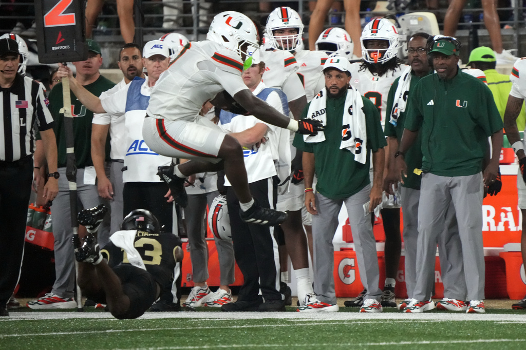 Miami tight end Elija Lofton, top, hurdles Wake Forest defensive back Ashaad Williams, bottom, during the first half of an NCAA college football game in Winston-Salem, N.C., Friday, Sept. 18, 2026. (AP Photo/Chuck Burton)