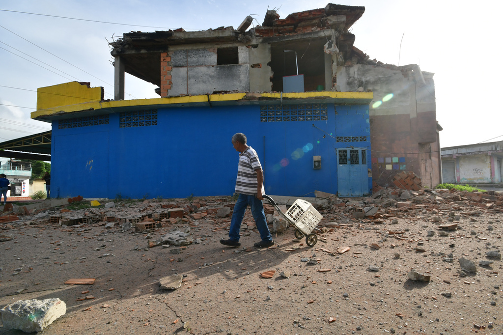 A man walks past a damaged home in Moron, near the epicenter of two earthquakes that struck Venezuela the day before, Thursday, June 25, 2026. (AP Photo/Jacinto Oliveros)