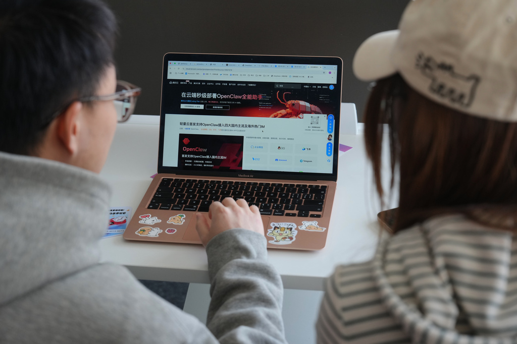 A staff member, left, helps a woman to install the RedClaw AI software on her laptop at an office in Beijing on March 22, 2026. (AP Photo/Andy Wong)