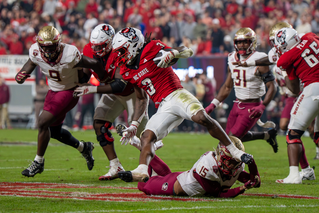 North Carolina State running back Hollywood Smothers (3) is tripped by Florida State defensive back Shamar Arnoux (15) during the first half of an NCAA college football game Friday, Nov. 21, 2025, in Raleigh, N.C. (AP Photo/David Yeazell)