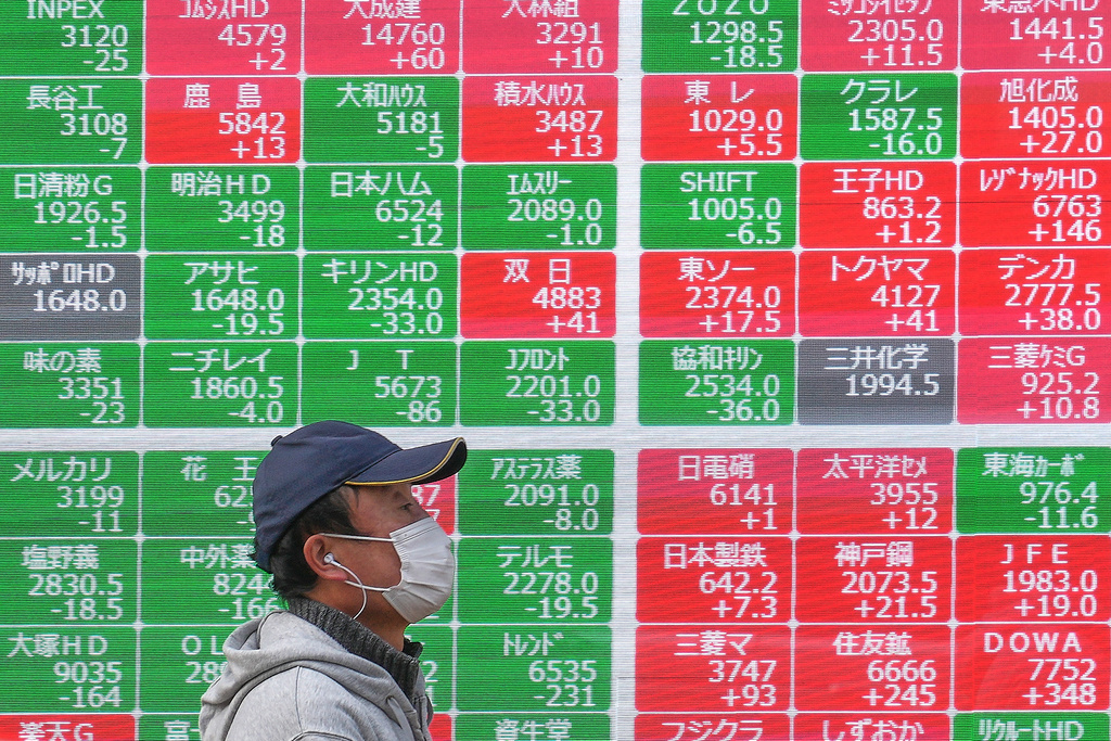 A person walks in front of an electronic stock board showing Japan's Nikkei index at a securities firm, Monday, Dec. 29, 2025, in Tokyo. (AP Photo/Eugene Hoshiko)