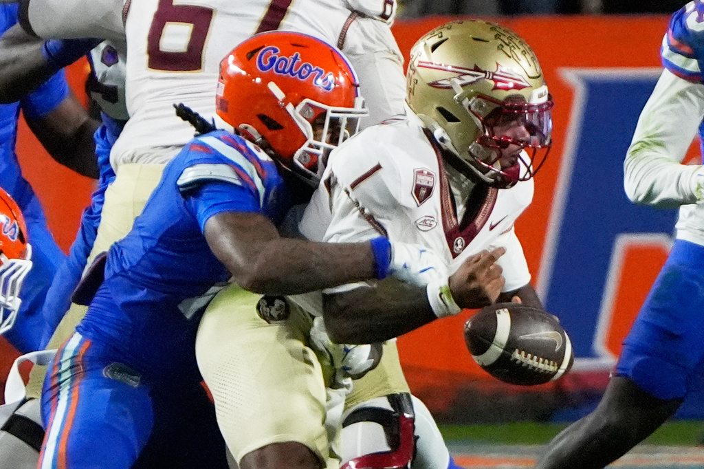 Florida State quarterback Tommy Castellanos, right, fumbles the ball as he is hit by Florida safety Bryce Thornton during the first half of an NCAA college football game, Saturday, Nov. 29, 2025, in Gainesville, Fla. (AP Photo/John Raoux)