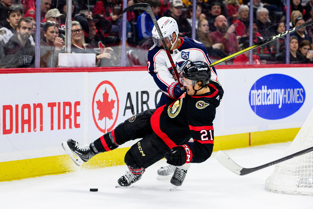 Columbus Blue Jackets' Brendan Smith (7) checks Ottawa Senators' Nick Cousins (21) during second period NHL hockey action in Ottawa on Monday, Dec. 29, 2025. (Spencer Colby/The Canadian Press via AP)