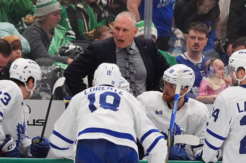 Toronto Maple Leafs head coach Craig Berube, center top, speaks to the bench during the second period of an NHL hockey game against the Dallas Stars, Sunday, Dec. 21, 2025, in Dallas. (AP Photo/LM Otero)