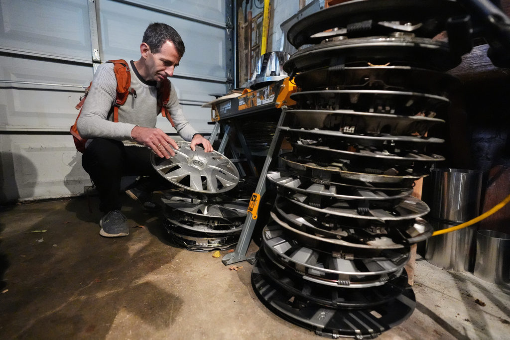 Cyclist Barnaby Wickham sorts through his collection of hubcaps stored in his garage, Thursday, Dec. 11, 2025, at his home in Baltimore. (AP Photo/Stephanie Scarbrough)