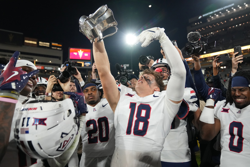 Arizona linebacker Carter Jones (18) celebrates by holding up The Territorial Cup after defeating Arizona State during an NCAA college football game, Friday, Nov. 28, 2025, in Tempe, Ariz. (AP Photo/Rick Scuteri)