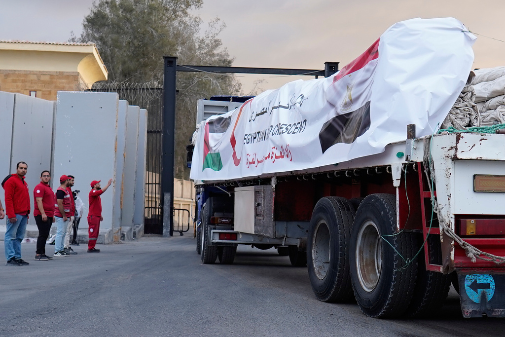 Egyptian Red Crecent members monitor trucks carrying humanitarian aids as they enter the Rafah crossing between Egypt and the Gaza Strip, following an agreement between Israel and Hamas on a ceasefire, Sunday, Oct. 12, 2025. (AP Photo/Mohamed Arafat)