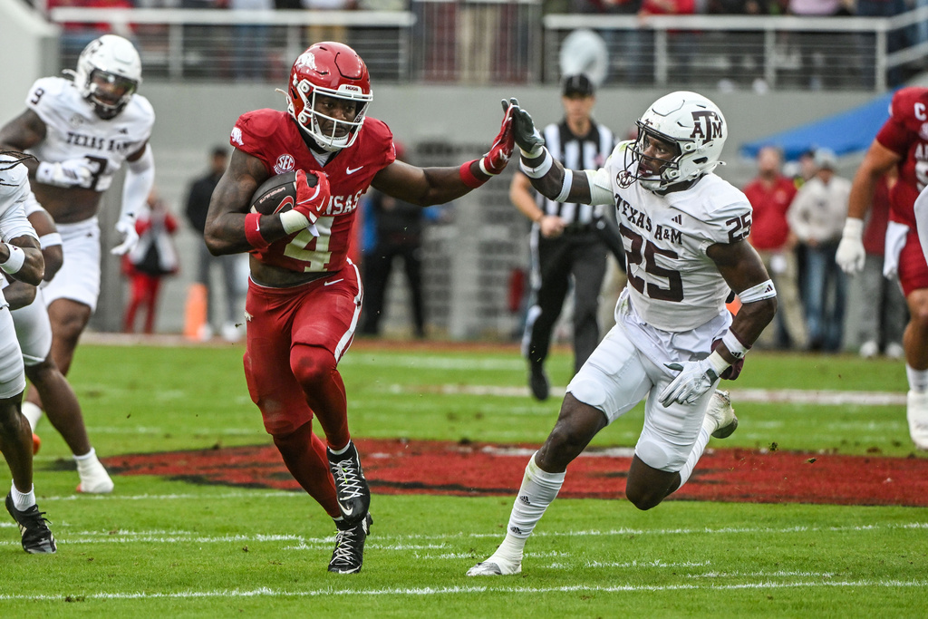 Arkansas running back Mike Washington Jr. (4) tries to get past Texas A&M defensive back Dalton Brooks (25) as he runs for a big gain during the first half of an NCAA college football game Saturday, Oct. 18, 2025, in Fayetteville, Ark. (AP Photo/Michael Woods)