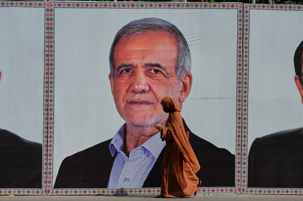 A woman walks past a welcoming billboard featuring Iranian President Masoud Pezeshkian along a roadside in Islamabad, Pakistan, Tuesday, June 23, 2026. (AP Photo/Anjum Naveed)