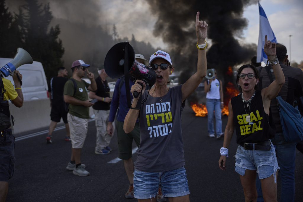 Demonstrators block a road during a protest demanding the immediate release of hostages held by Hamas and calling for the Israeli government to reverse its decision to take over Gaza City and other areas in the Gaza Strip, near Jerusalem, Israel, Sunday, Aug. 17, 2025. (AP Photo/Ohad Zwigenberg)