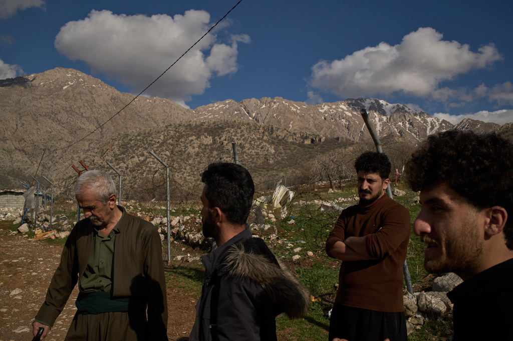 Ako Abdul Rahman, 22, right, an Iraq-Iran cross-border smuggler, chats with local colleagues at a compound in a village in the mountainous Kurdish region near Halabja, Iraq, Tuesday, March 17, 2026. (AP Photo/Leo Correa)