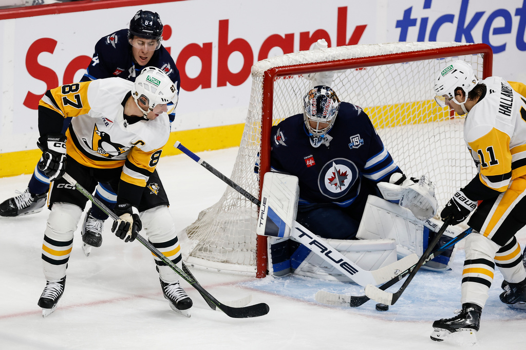 Pittsburgh Penguins' Sidney Crosby (87) makes the pass in front of Winnipeg Jets goaltender Eric Comrie (1) during the second period of an NHL hockey game, Saturday, Nov. 1, 2025, in Winnipeg, Manitoba. (John Woods/The Canadian Press via AP) \