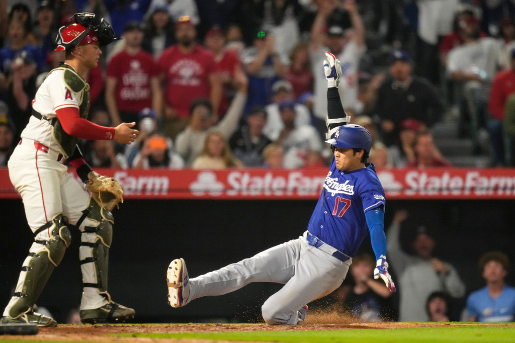 Los Angeles Dodgers' Shohei Ohtani, right, scores on his two-run triple after a throwing error as Los Angeles Angels catcher Logan O'Hoppe stands at the plate during the eighth inning of a baseball game Saturday, May 16, 2026, in Anaheim, Calif. (AP Photo/Mark J. Terrill) CORRECTION: After official review, changed from three-run inside-the-park home run to two-run triple after a throwing error