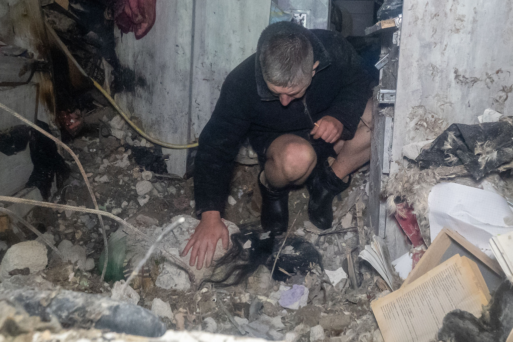 A man reacts at the dead body his wife after his residential building was damaged by a Russian attack in Kharkiv, Ukraine, late Sunday, Nov. 23, 2025. (AP Photo/Andrii Marienko)