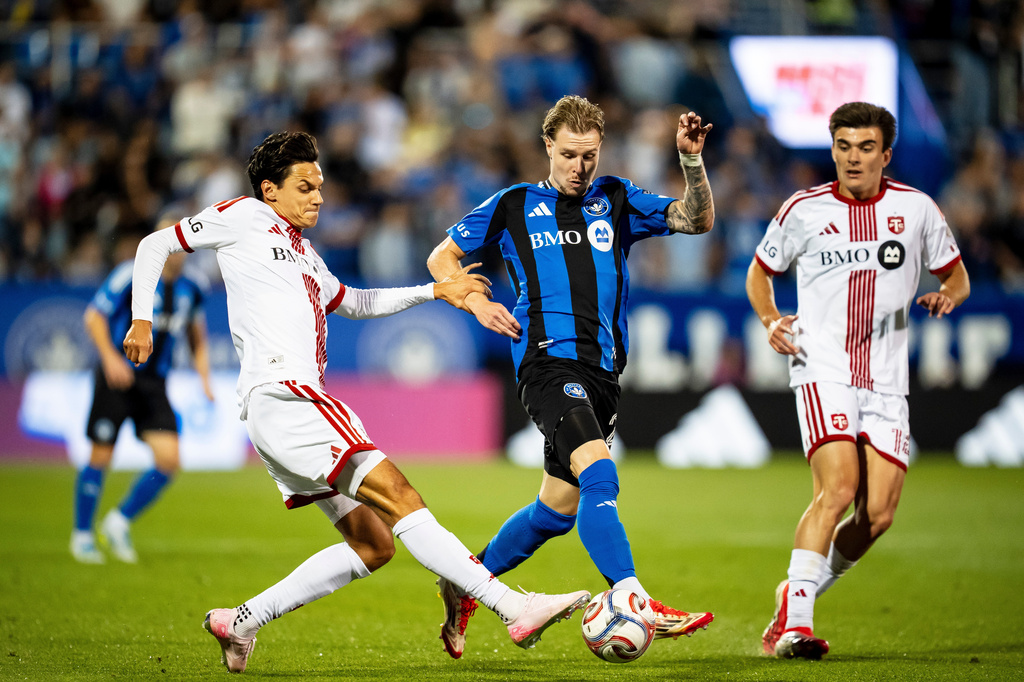 CF Montreal's Dawid Bugaj, center, is defended by Toronto FC's Daniel Salloi, left, and Alonso Coello (14) during the second half of an MLS soccer game, in Montreal on Thursday, July 16, 2026. (Christopher Katsarov/The Canadian Press via AP)