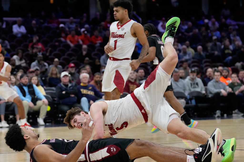 Miami (Ohio) guard Peter Suder (5) falls over Massachusetts forward Jr. Dwayne Wimbley (2) in the first half of a basketball game in the quarterfinals of the Mid-American Conference tournament, Thursday, March 12, 2026, in Cleveland. (AP Photo/Sue Ogrocki)