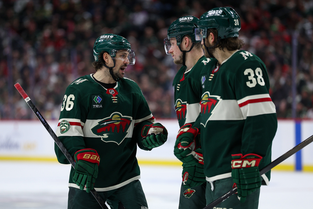 Minnesota Wild right wing Mats Zuccarello, left, talks with right wing Vladimir Tarasenko and right wing Ryan Hartman before a face-off against the Detroit Red Wings during the third period of an NHL hockey game Thursday, Jan. 22, 2026, in St. Paul, Minn. (AP Photo/Matt Krohn)
