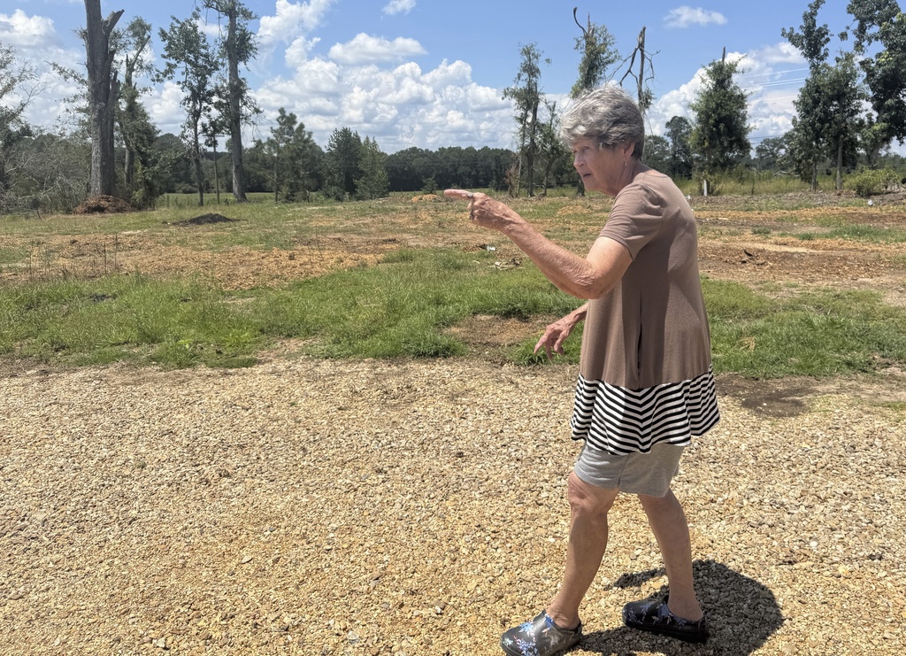 Dana Grimes, who lost her home, garage and car to a March tornado, walks across her property in Jayess, Miss., Thursday, Aug. 14, 2025. (AP Photo/Sophie Bates)