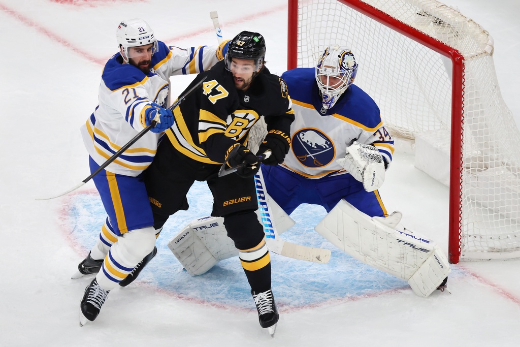 Buffalo Sabres' Conor Timmins (21) defends against Boston Bruins' Mark Kastelic (47) in front of Sabres goaltender Alex Lyon (34) during the first period of an NHL hockey game, Saturday, Oct. 11, 2025, in Boston. (AP Photo/Michael Dwyer)