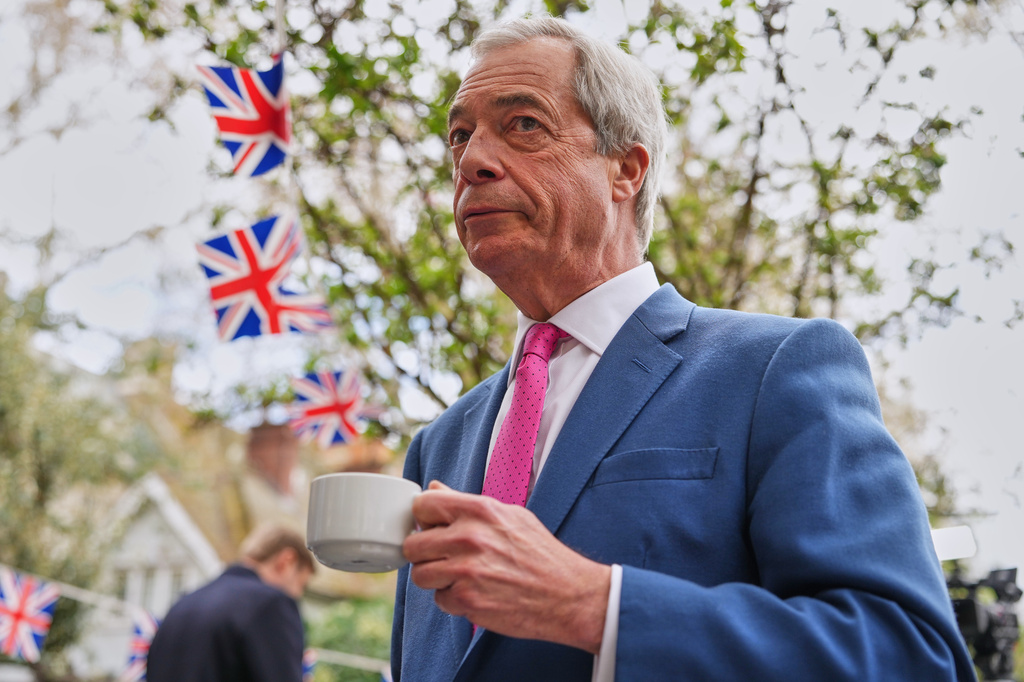 FILE - Nigel Farage, the leader of Reform UK, drinks a cup of tea as he meets supporters after a news conference in London on April 2, 2026. (AP Photo/Kirsty Wigglesworth, File)
