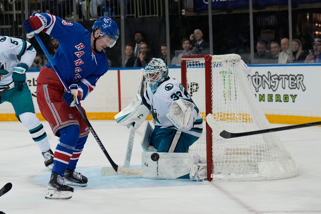 San Jose Sharks goaltender Alex Nedeljkovic, right, defends the net against New York Rangers' Alexis Lafrenière during the second period of an NHL hockey game in New York, Thursday, Oct. 23, 2025. (AP Photo/Seth Wenig)