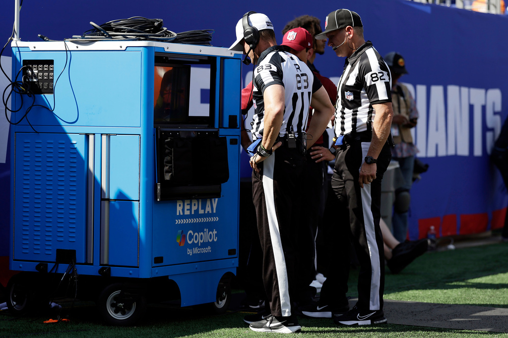 FILE - Referee Shawn Hochuli (83) and back judge Jimmy Russell (82) review a play at the instant replay cart during an NFL football game between the Los Angeles Chargers and the New York Giants, Sunday, Sept. 28, 2025, in East Rutherford, N.J. (AP Photo/Adam Hunger, File)