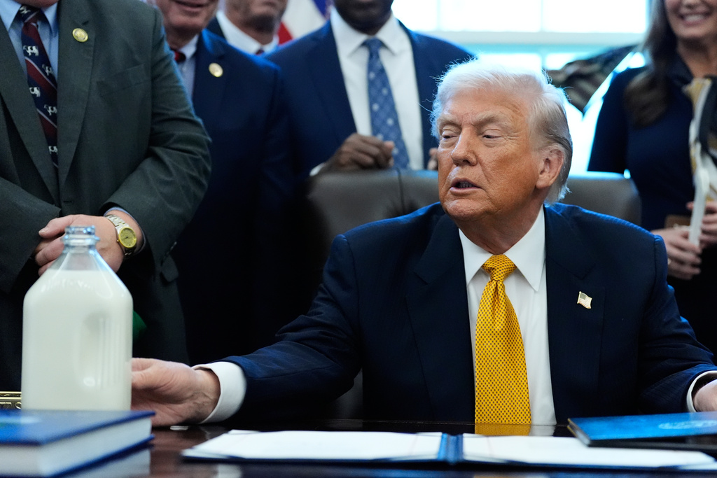 President Donald Trump touches a container of milk as he speaks in the Oval Office of the White House, Wednesday, Jan. 14, 2026, in Washington. (AP Photo/Alex Brandon)