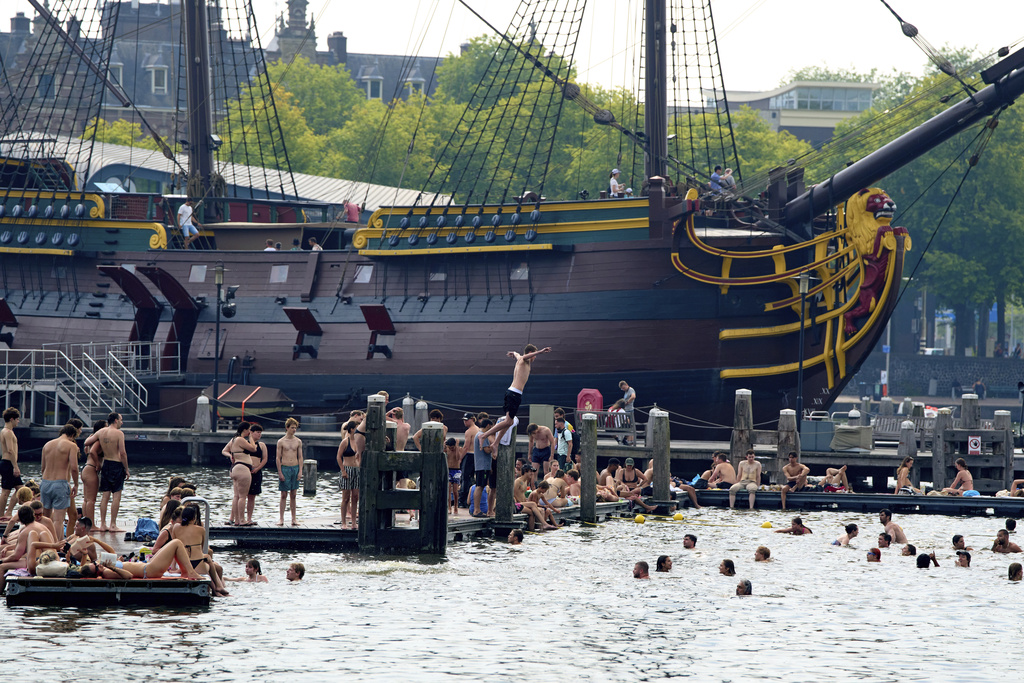 People cool down in the water during hot weather near the Maritime Museum in Amsterdam, Netherlands, Wednesday, Aug. 13, 2025. (AP Photo/Peter Dejong)