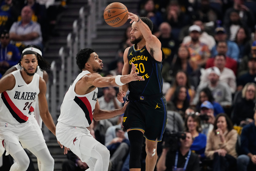 Golden State Warriors guard Stephen Curry (30) passes the ball while defended by Portland Trail Blazers forward Toumani Camara (33) during the first half of an NBA Cup basketball game, Friday, Nov. 21, 2025, in San Francisco. (AP Photo/Godofredo A. Vásquez)