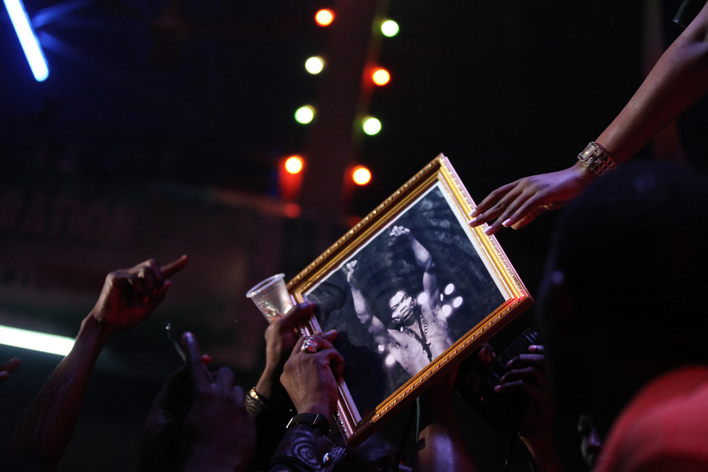 FILE - Singer Tiwa Savage hands back a portrait of Fela Anikulapo-Kuti to a fan at the New Afrika Shrine in Lagos, Nigeria, on Sunday, Oct. 21, 2012. (AP Photo/Jon Gambrell, File)