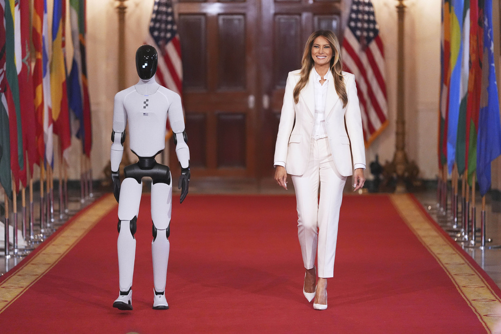 First lady Melania Trump arrives, accompanied by a robot, to attend the "Fostering the Future Together Global Coalition Summit," with other first spouses, at the White House, Wednesday, March 25, 2026, in Washington. (AP Photo/Jacquelyn Martin)