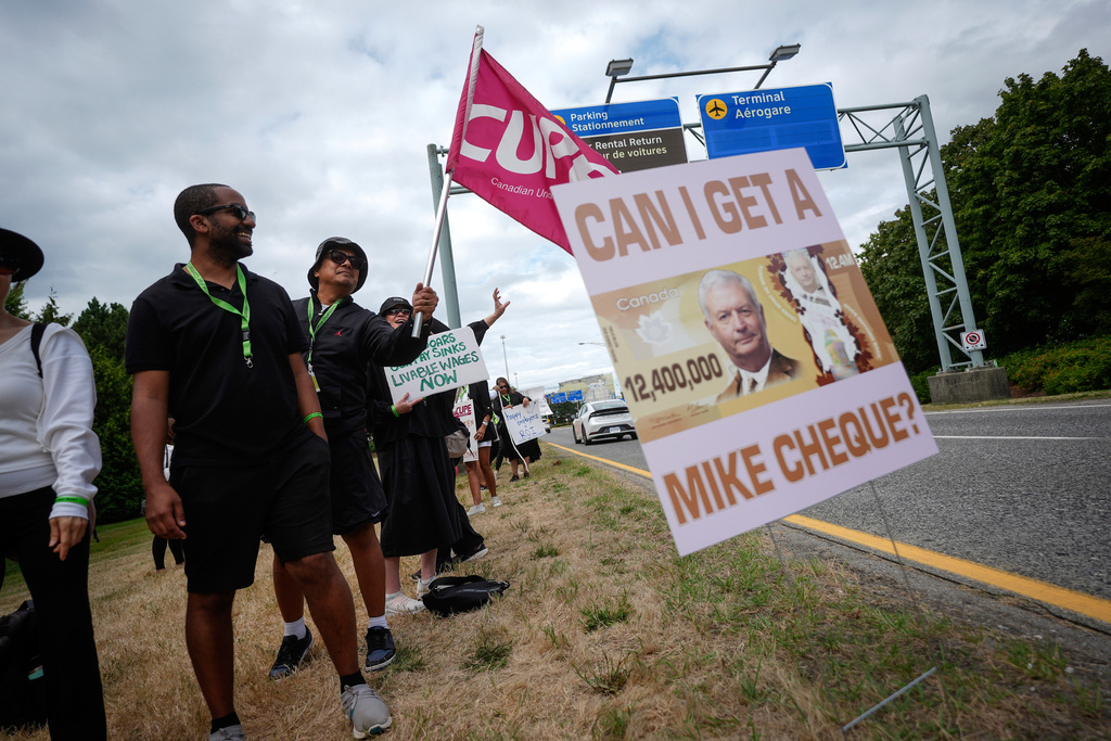 A sign with a photo of Air Canada CEO Michael Rousseau on it is seen as striking Air Canada flight attendants rally at Vancouver International Airport, in Richmond, British Columbia, Monday, Aug. 18, 2025. (/Darryl Dyck/The Canadian Press via AP)
