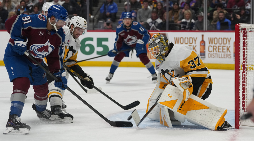 Colorado Avalanche center Nazem Kadri, front left, puts a shot on Pittsburgh Penguins goaltender Arturs Silovs, right, as defenseman Declan Carlile covers in the third period of an NHL hockey game, Friday, Oct. 16, 2026, in Denver. (AP Photo/David Zalubowski)