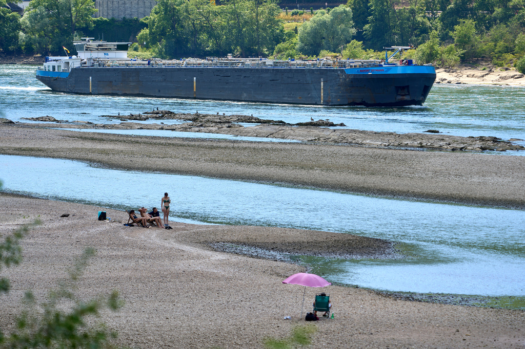 People visit the banks of the Rhine near the Loreley as a cargo ship passes by in Goarshausen, Germany, Saturday, June 20, 2026. (Thomas Frey/dpa via AP)