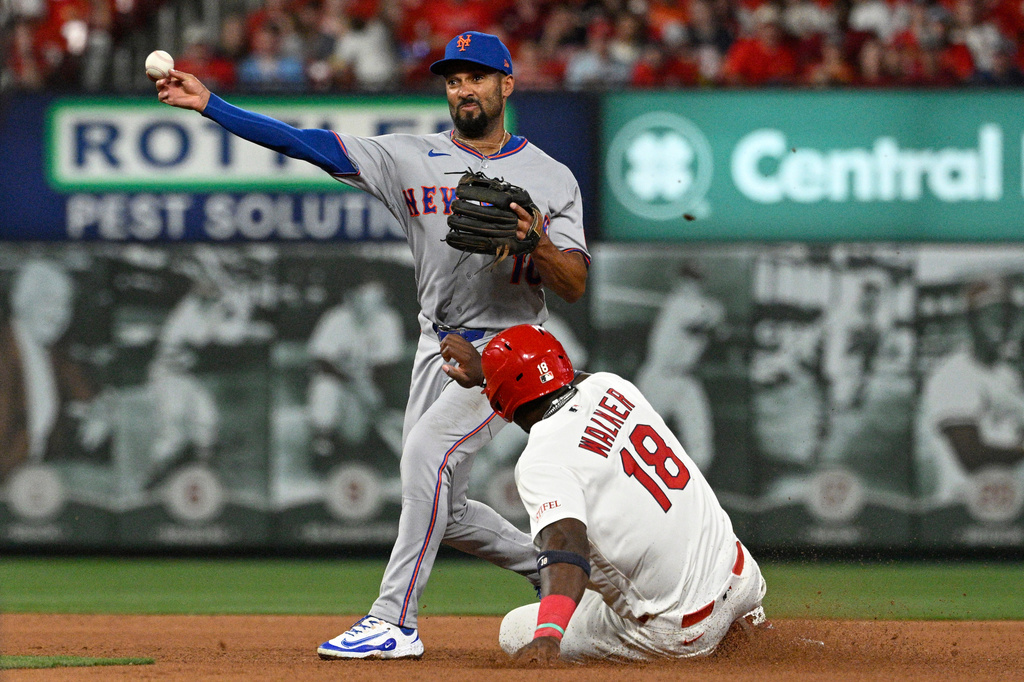 St. Louis Cardinals' Jordan Walker (18), right, is out at second base as New York Mets second baseman Marcus Semien, left, turns a double play in the fourth inning of a baseball game, Monday, March 30, 2026, in St. Louis. (AP Photo/Joe Puetz)