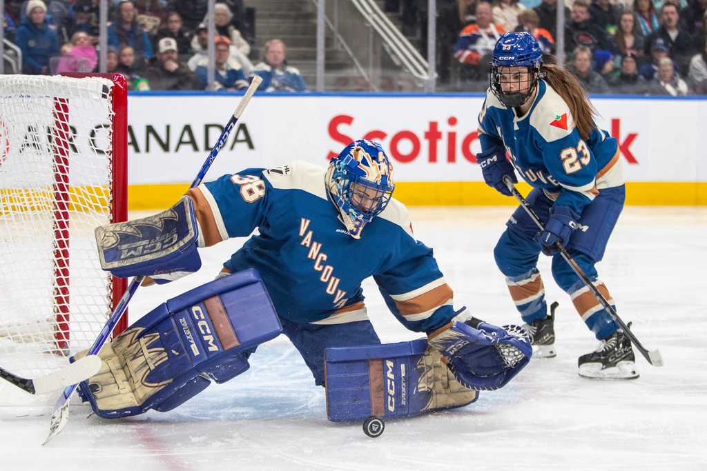 Vancouver Goldeneyes goalie Emerance Maschmeyer (38) keeps out a Minnesota Frost puck as Mellissa Channell-Watkins (23) looks on during the first period of an PWHL game in Edmonton, Saturday, Dec. 27, 2025. (Amber Bracken/The Canadian Press via AP)