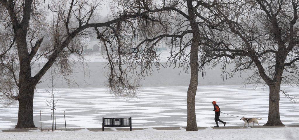 A runner and his dog circle a frozen Prospect Lake in Colorado Springs, Colo., Friday, Jan. 23, 2026, as snow and extremely cold weather hits the Pikes Peak Region. (Christian Murdock/The Gazette via AP)