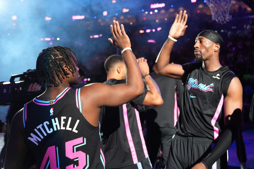 Miami Heat center Bam Adebayo, right, greets guard Davion Mitchell (45) before an NBA basketball game against the Golden State Warriors, Wednesday, Nov. 19, 2025, in Miami. (AP Photo/Lynne Sladky)