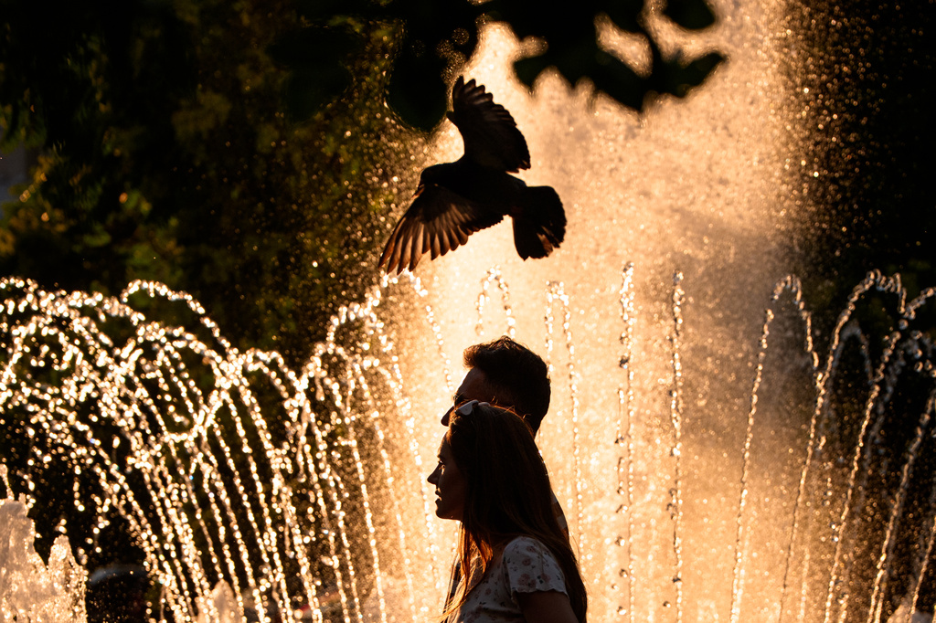 A couple walks by a public fountain on a torrid day, as the National Weather forecaster issued an extreme heat code red warning for parts of the country, in the coming days in Bucharest, Romania, Saturday, June 27, 2026. (AP Photo/Andreea Alexandru)